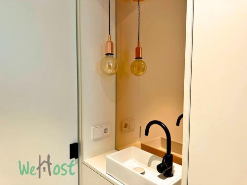 La salle de bains est pourvue d'un lavabo et de deux lumières. dans l'établissement Vieux-Port - LB - PB - Vieux Beautiful apartment beach 4 people, à Biarritz