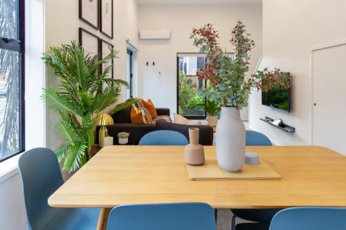 a dining room table with blue chairs and a vase with flowers at Urban Comfort on Durham St, Walk Everywhere! in Christchurch