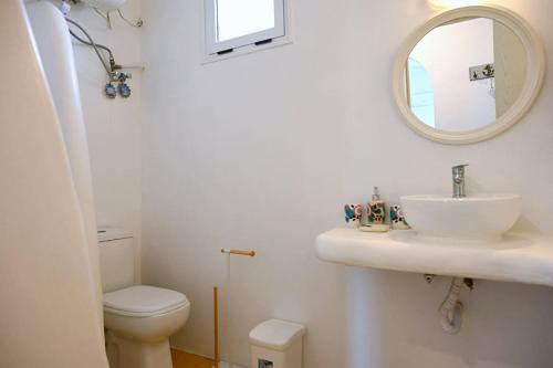 a bathroom with a sink and a toilet and a mirror at Simousi Beach House in Kithnos
