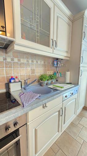 a kitchen with white cabinets and a sink at Ferienhaus Küstenzeit – Ihr Refugium in Trassenheide in Trassenheide