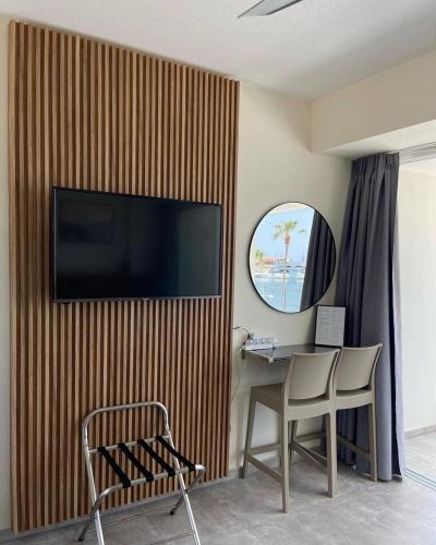 a living room with a television on a wooden wall at Harbour Lights Studio Apartments in Paphos City