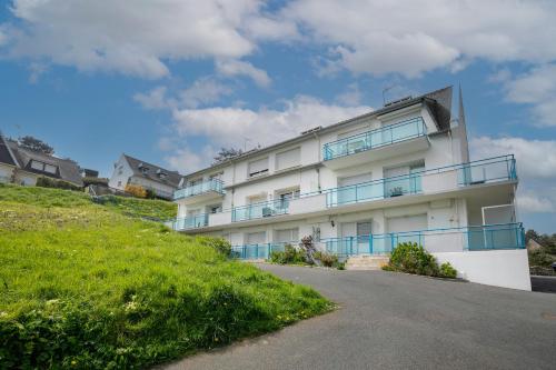 a white building with blue balconies on a hill at Appartement en front de mer in Plérin