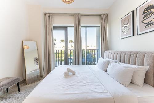 a bedroom with a large white bed and a balcony at HAVN - 2 Bedroom in Bayshore, Dubai Creek Harbour in Dubai