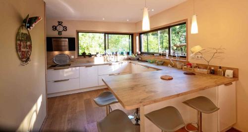 une grande cuisine avec un grand comptoir en bois dans l'établissement L'Ecrin de Bois - Maison d'architecte avec Spa sur un grand terrain arboré, à Cahuzac-sur-Vère