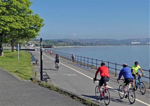 a group of people riding bikes down a road next to a lake at Velo Club Mumbles in Oystermouth