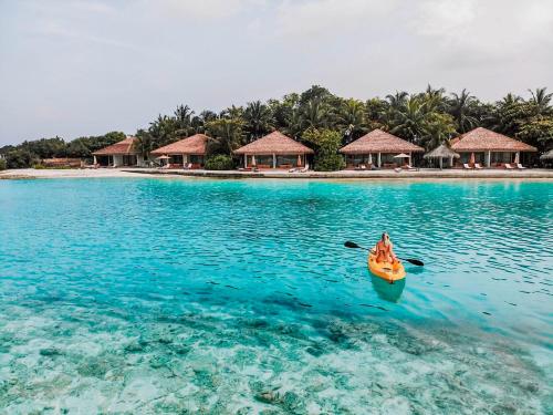 a person in a kayak in the water near an island at Cinnamon Dhonveli Maldives in North Male Atoll