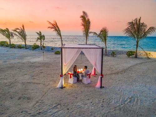 a couple sitting at a table in a tent on the beach at Cinnamon Dhonveli Maldives in North Male Atoll
