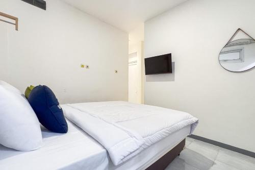 a white bedroom with a bed with a blue pillow at Urbanview Syariah Sentul City Bogor in Cibitung