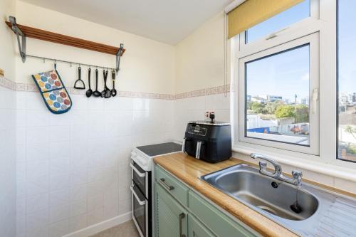 a kitchen with a sink and a window at Casa Sirena Apartment in Fistral, Newquay in Newquay