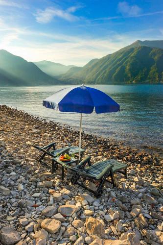 a bench and an umbrella on a rocky beach at Appartamenti Portobello in Lezzeno