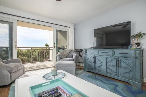 a living room with a large entertainment center with a tv at Beachwalk 205- After Dune Delight condo in Pine Knoll Shores