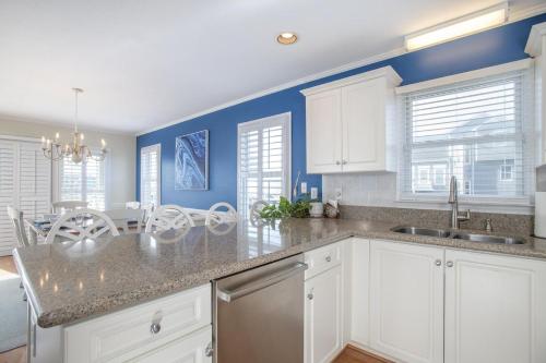 una cucina con armadi bianchi e pareti blu di Azure home a Emerald Isle