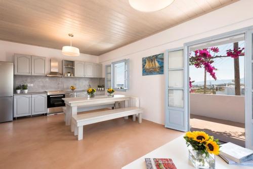 una cocina con armarios blancos y una mesa con flores en Menta I in the heart of Naousafree parkingParos, en Naousa