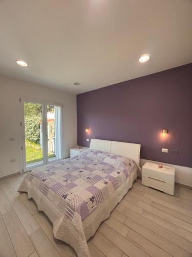 a bedroom with a large bed with a purple wall at Sunrise Home in Porto Ottiolu