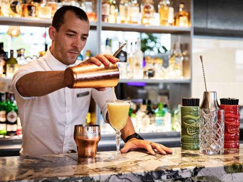 a man making a drink at a bar at Pullman Paris Centre - Bercy in Paris
