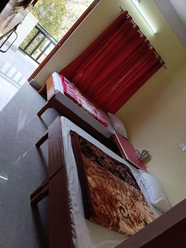 a bedroom with a bed and a red window at Devlok Tourist Complex in Barkot
