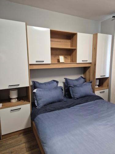a bedroom with a bed with white cabinets and blue pillows at V&S apartments 1 in Sliven