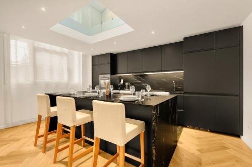 une cuisine avec un îlot noir et des chaises blanches dans l'établissement Nero Marquina - Climatisé proche métro, à Toulouse