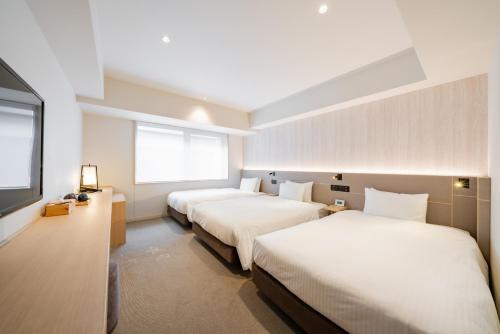 a hotel room with two beds and a flat screen tv at Keio Prelia Hotel Kyoto Karasuma-Gojo in Kyoto