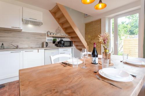 - une cuisine avec une table en bois, des assiettes et des verres à vin dans l'établissement Gîte Avec Jacuzzi Chic & Cosy entre Caen et la Mer en Normandie, à Biéville-Beuville