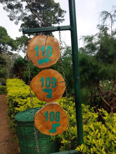 three wooden signs hanging from a pole with a basket at Nature Zone Jungle Resort in Munnar