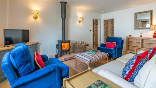 sala de estar con sillas azules y chimenea en The Old Tractor Shed, en Cheltenham
