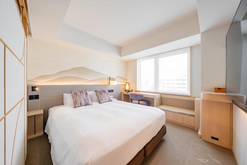 a bedroom with a large white bed and a window at Keio Prelia Hotel Kyoto Karasuma-Gojo in Kyoto
