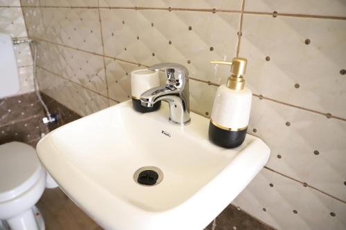 a white bathroom sink with a gold bottle on it at Bujtina Ethan Perondi in Kuçovë