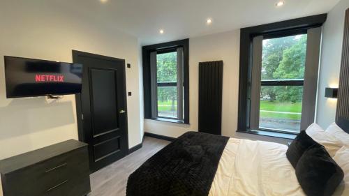 a bedroom with a bed with a television and windows at 3M Luxury Living in Preston