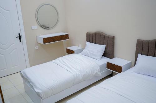a bedroom with two beds and a mirror on the wall at موتيل رامي سكاي Motel Rami Sky in Erbil