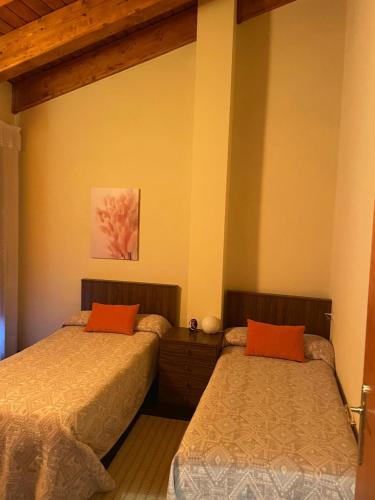 a bedroom with two beds with orange pillows at Casa Massó in Anserall