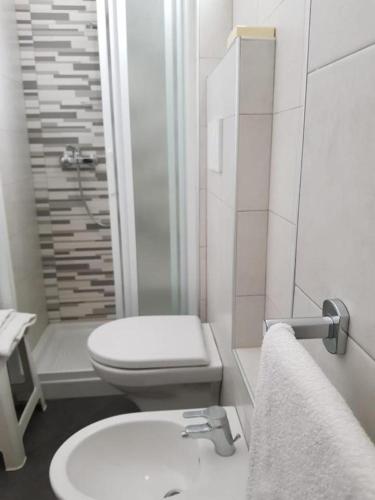 a white bathroom with a toilet and a sink at Alevon Hotel in Rimini