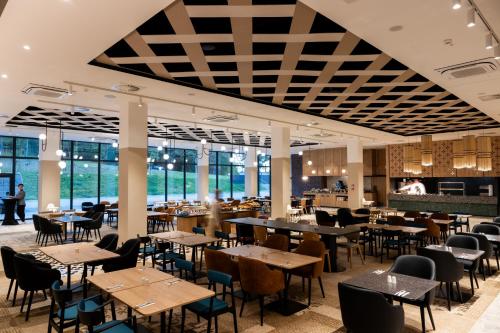 a dining room with tables and chairs and windows at Mercure Szczyrk Resort in Szczyrk