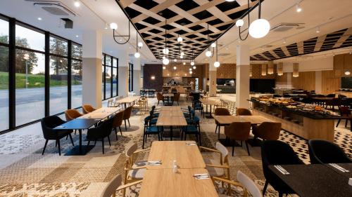 a restaurant with wooden tables and chairs and windows at Mercure Szczyrk Resort in Szczyrk