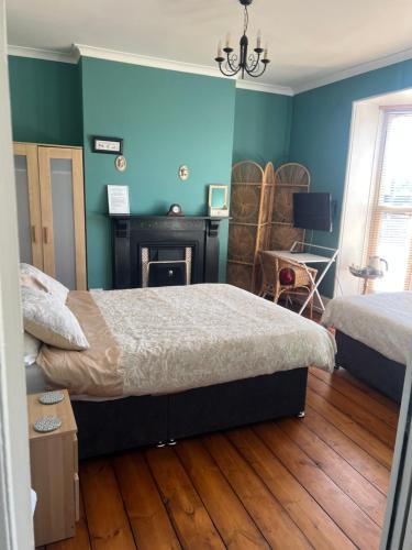 two beds in a room with blue walls and wooden floors at The Townhouse B and B free continental breakfast included in Aylesbury