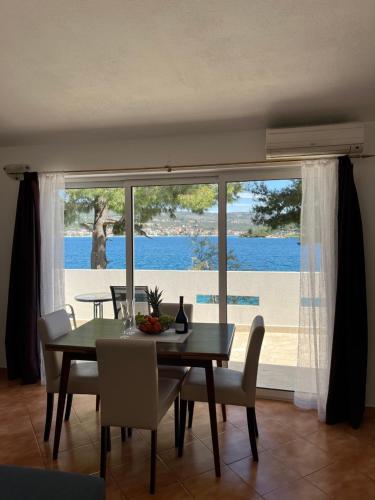 a dining room with a table and chairs and a large window at Bronislovas holiday home in Rogoznica