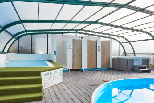 a gym with a glass ceiling and a swimming pool at Campsie Glen Holiday Park in Glasgow