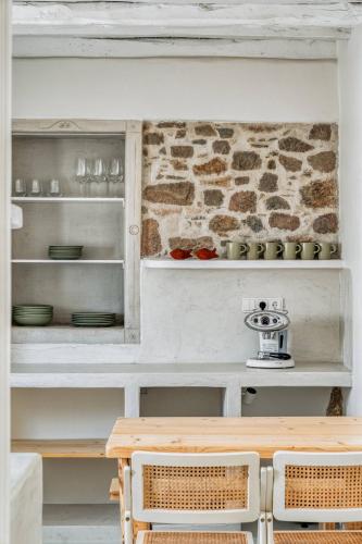 Un comedor con una mesa y una pared de piedra. en My Secret Mojo 1, en Serifos Chora