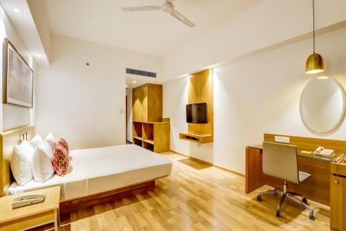 a hotel room with a bed and a desk at Lemon Tree Hotel Electronics City in Bengaluru