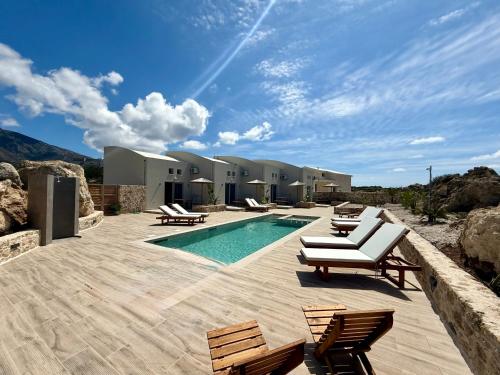 una piscina con sedie a sdraio accanto a una casa di Cove Elafonisi Apartments a Elafonisi