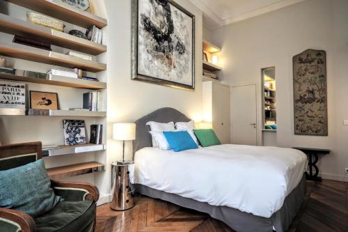 une chambre avec un grand lit blanc et une chaise dans l'établissement Richelieu ChicSuites, à Paris