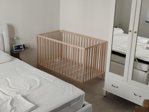 a crib in a room with a bed and a mirror at Ruffoli-Home a 300 m dal mare in Rosignano Solvay