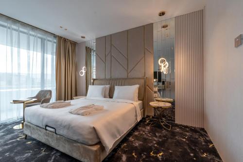 a bedroom with a large bed and a large window at Elania Resort & Spa in Cluj-Napoca