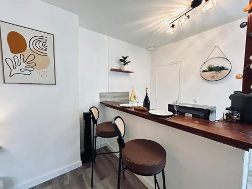 - une cuisine avec deux tabourets et un bar dans une pièce dans l'établissement Chez Cath Studio neuf cosy proche centre-ville, à Reims