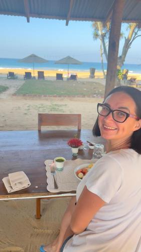a woman sitting at a table with a plate of food at Villa ArthurCC in Hikkaduwa