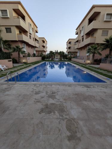 an empty swimming pool in front of some apartment buildings at Janat House in Marrakech