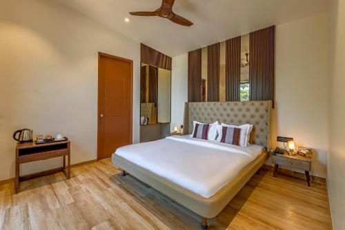 a bedroom with a large white bed and wooden floors at Hillside Harrier Couple's Retreat in Āmbavna