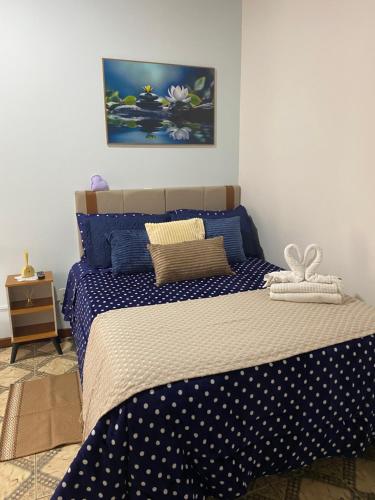 a bedroom with a bed with blue and white sheets at Suítes Aconchego dos Pinhais in Santo Antônio do Pinhal