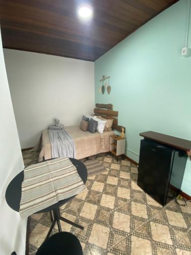 a bedroom with a bed and a table and a piano at Suítes Aconchego dos Pinhais in Santo Antônio do Pinhal