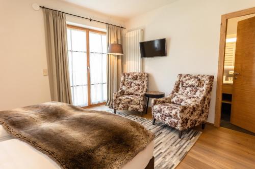 ein Schlafzimmer mit einem Bett und zwei Stühlen und einem Fernseher in der Unterkunft Der Unterwirt Guesthouse and Restaurant in Klausen